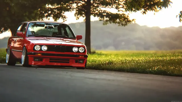 Red BMW E30 with a low stance-car treatment and classic compact profile.