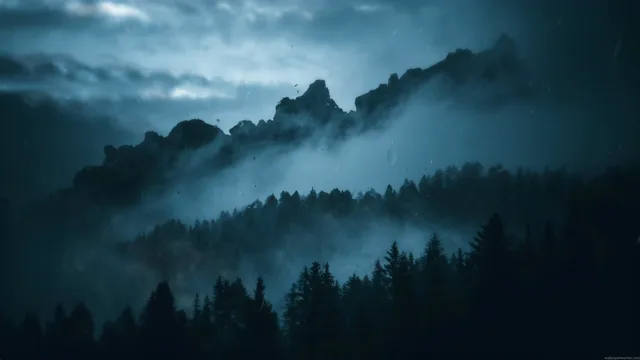 Pale mist layered between dark evergreen forests and blue mountains