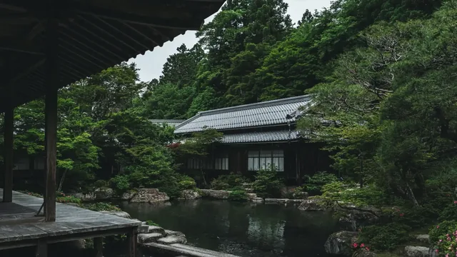Secluded temple house behind dense greenery beside a shaded reflective pond.