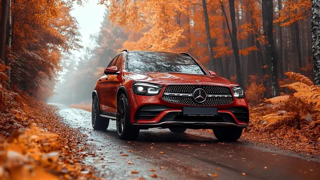 Red Mercedes-Benz GLC on a misty forest road covered with autumn leaves.