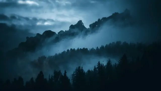Dark mountain peaks and pine forest layered through mist and rain