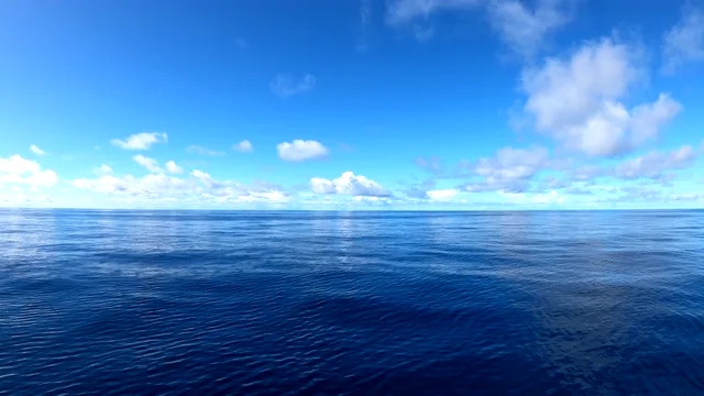 Sunlit cumulus clouds above a calm blue ocean beneath a wide open sky