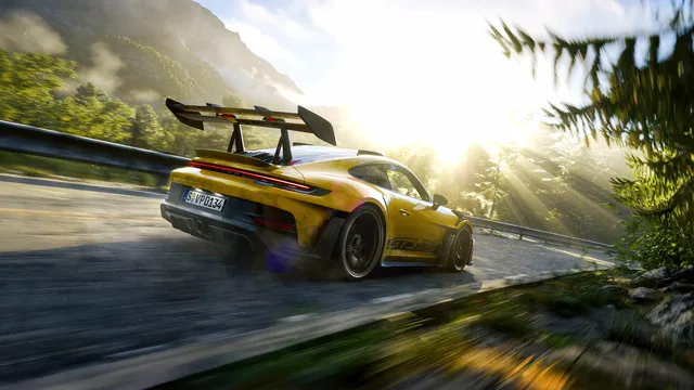 Yellow Porsche 911 GT3 RS driving on a sunlit mountain road
