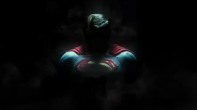 Superman standing in shadow with a faintly lit S emblem and smoke